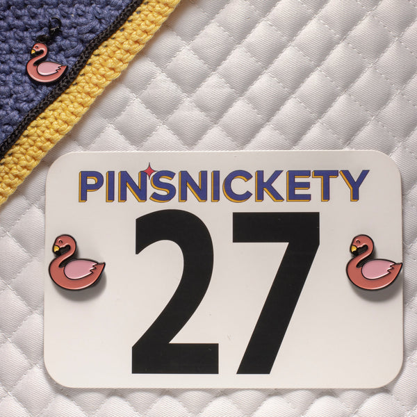 pinsnickety flamingo set with a bridle charm on a bonnet and horse show number pins on a saddle pad