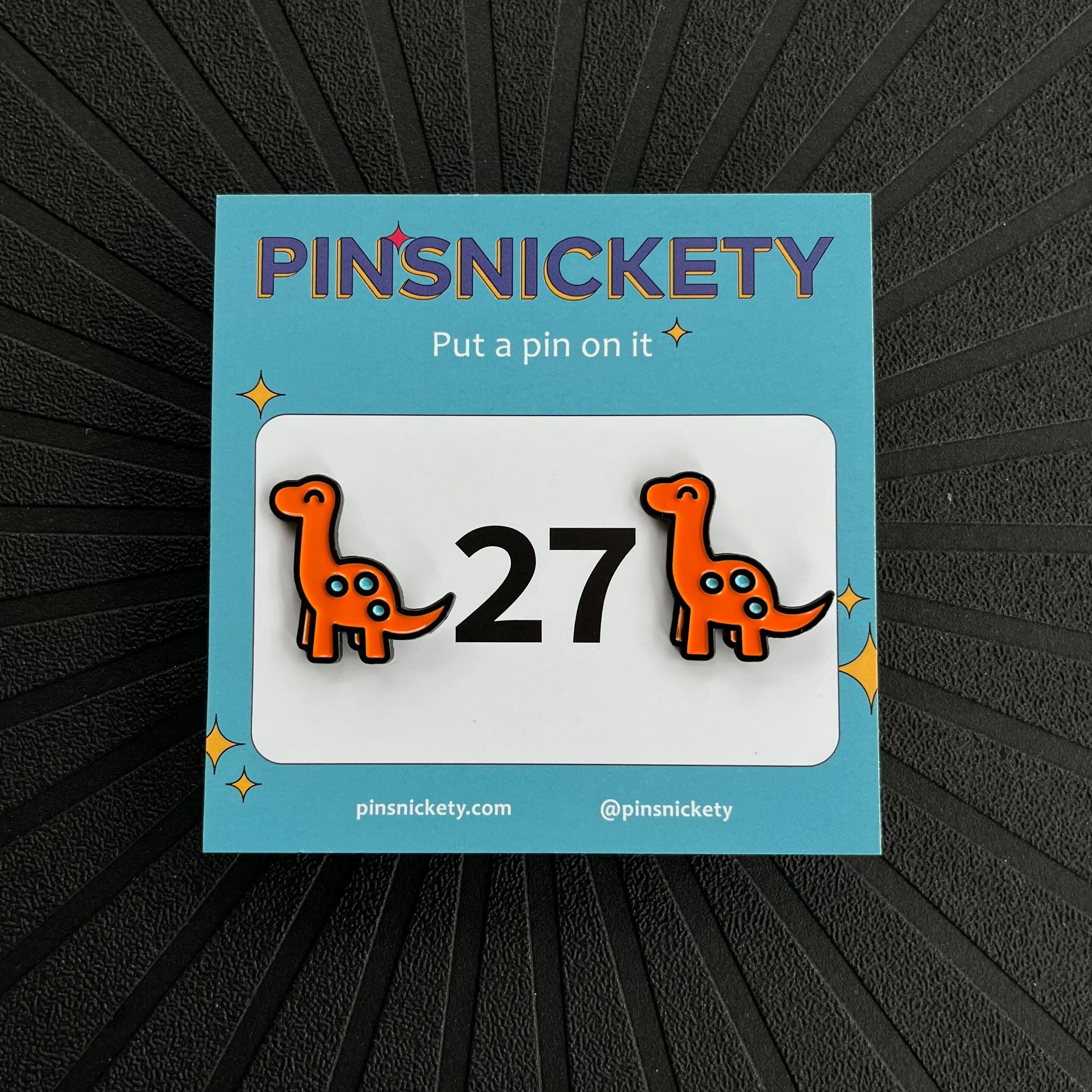 pinsnickety orange brontosaurus horse show number pins on a black background