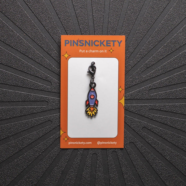 Pinsnickety rocket ship charm on its product packaging card